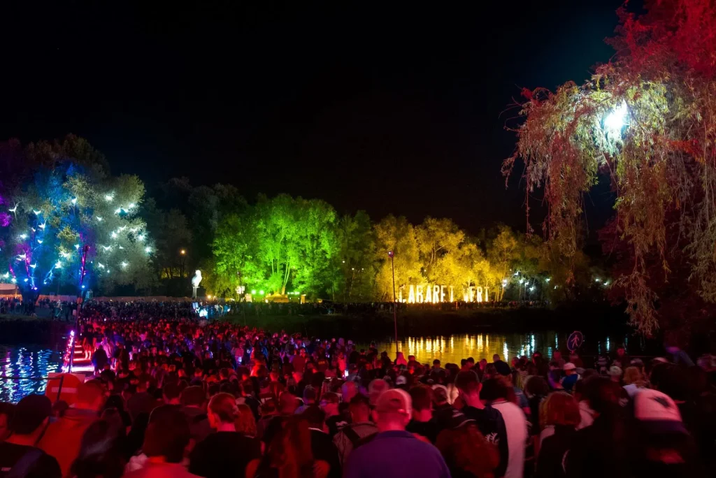 Cabaret Vert de nuit avec vue sur la foule des festivaliers qui traversent le pont sur la Meuse - Belles lumières colorées